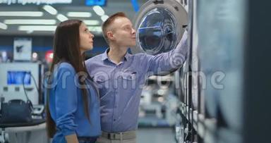 电器商店的男女青年选择买洗衣机回家。 打开门看着鼓